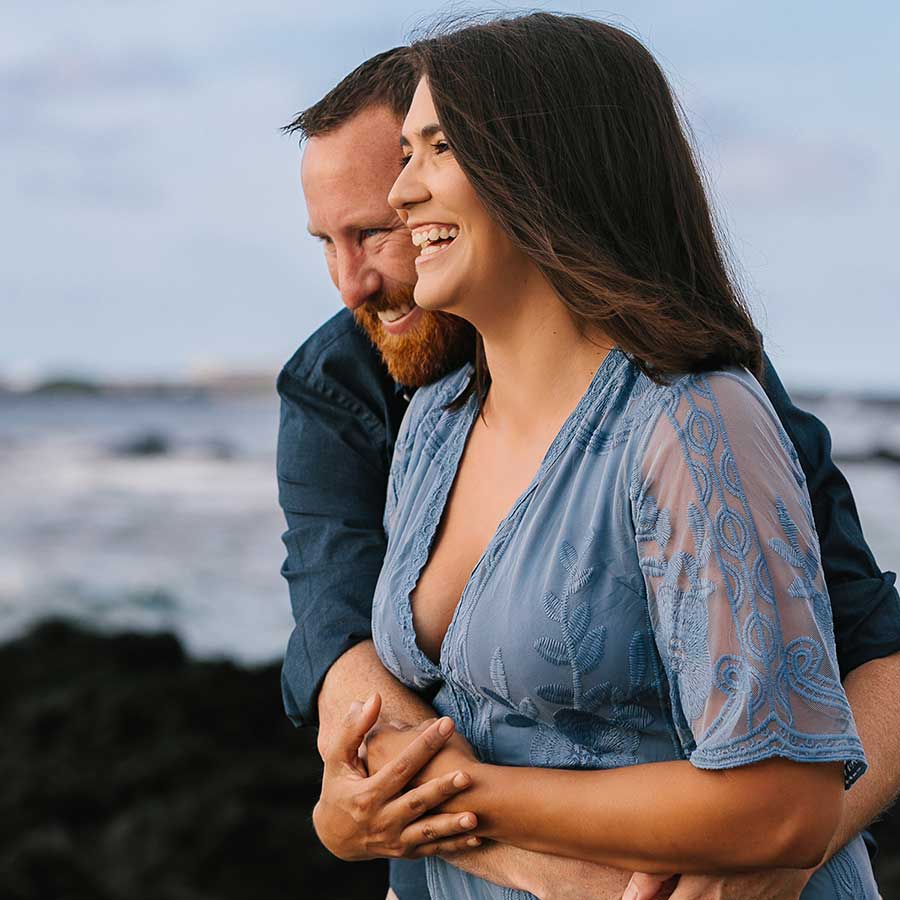 image of couple cuddling next to the beach