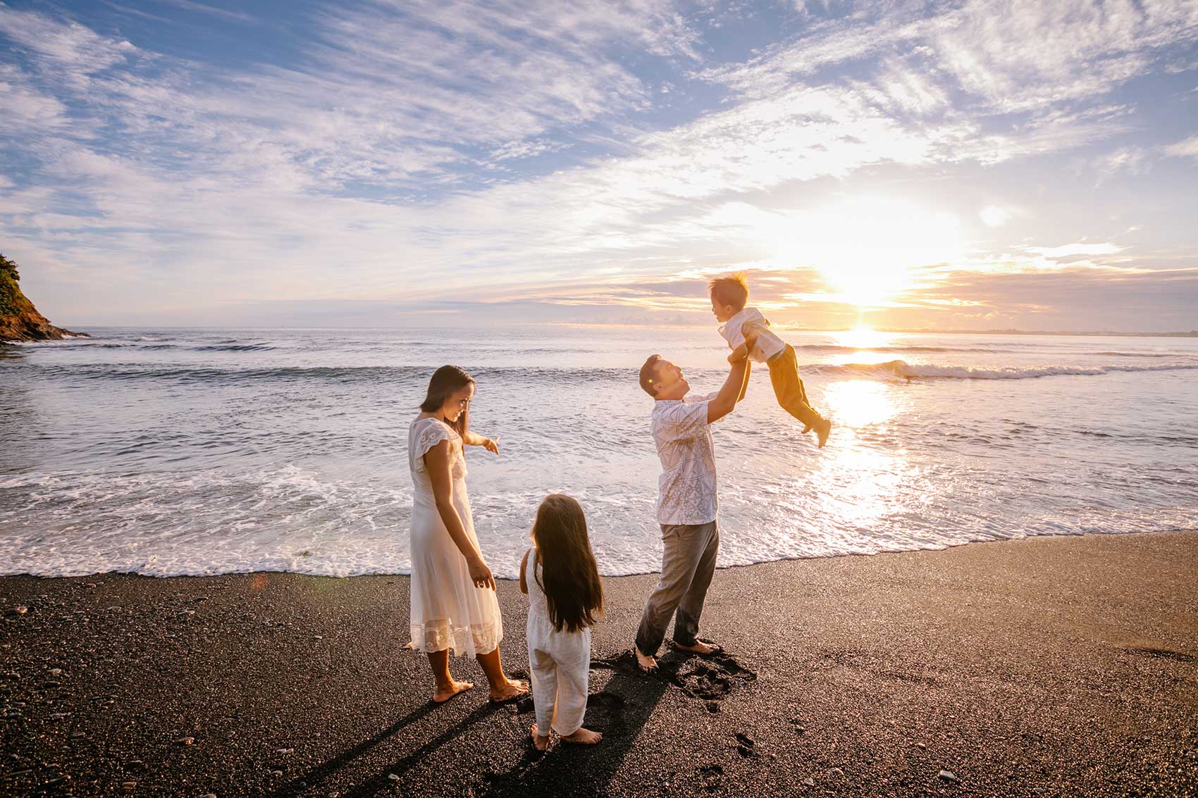 image of family of 4 playing next to the surf