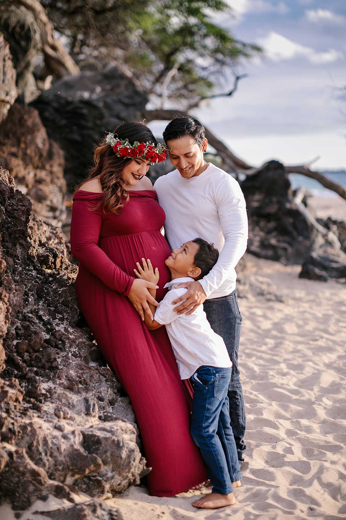 image of husband and pregnant wife with their daughter at the beach